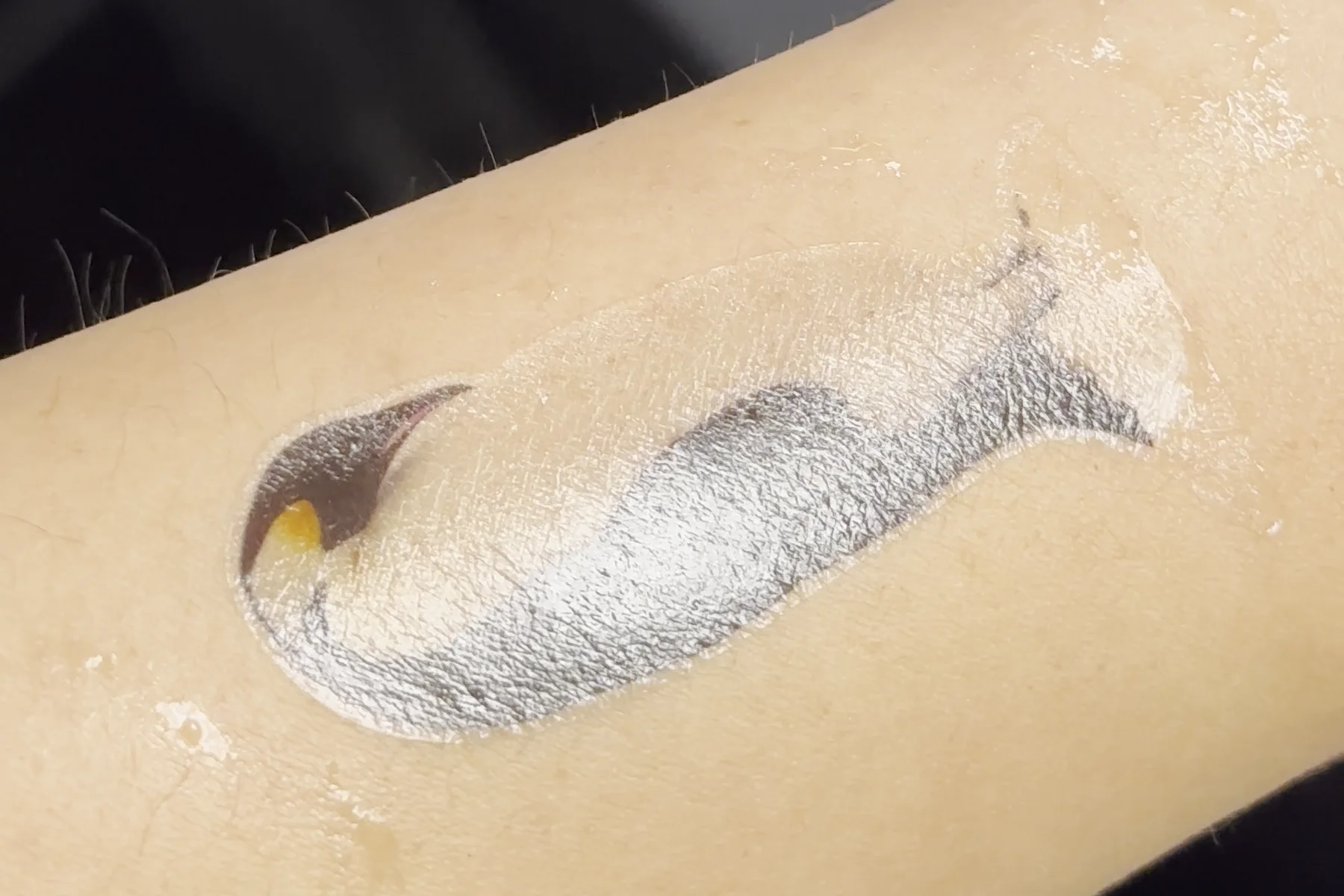 An emperor penguin painted on my forearm in white and grey, with a yellow beak
